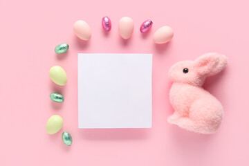 Beautiful Easter bunny, eggs, chocolate candies and blank card on pink background