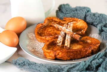 Plate with traditional homemade Torrijas, cinnamon stick,milk and eggs. Typical Lent and Easter dessert in Spain