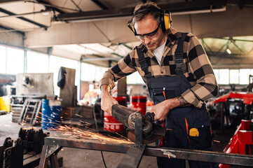 Dedicated worker wields his grinder while making a metal construction.