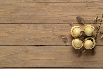 Easter eggs in nests with feathers and blooming branch on wooden background. Top view