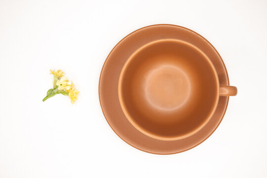 Xícara De Café Preto Com Espuma Dourada, Pires E Xicara Em Terracota, Bege, Marrom, Terra,  , Pequeno Ramalhete De Pequenas Flores Amarelas Fundo Branco