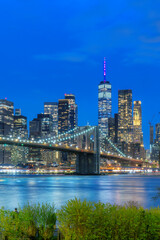Manhattan skyline and Brooklyn Bridge illuminated at night in New York City - 770063890