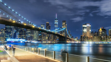 Manhattan skyline and Brooklyn Bridge illuminated at night in New York City - 770064029