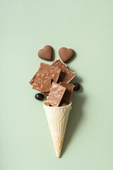 Waffle cone with chocolate flat lay, top view on pastel green backgroud