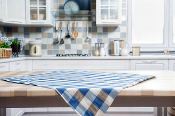 Modern kitchen setting with a blue and white checkered tablecloth on a wooden table, blurred background. High quality photo