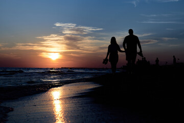 Serene Stroll: A Man and a Woman Walking on the Beach at Sunset