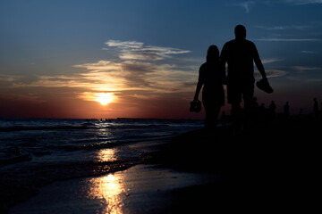Obraz na płótnie Canvas Silhouettes of Love: A Romantic Stroll Along the Sunset Beach