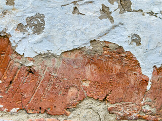 Close-up of a rough brick wall with peeling paint revealing the aged brick underneath.