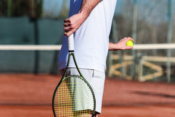 Close up of young boy with racket playing tennis on a clay court during a university tournament....