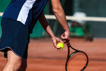 Detail of young boy with racket playing tennis on a clay court during a university tournament. the...