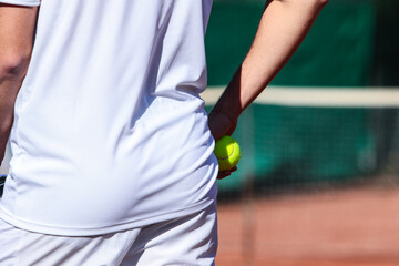 Close up of young boy with racket playing tennis on a clay court during a university tournament....