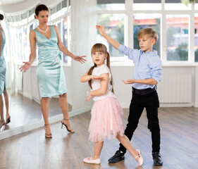 Boy and girl in pair train to dance vigorous hustle during classes. Children rehearse contemporary...