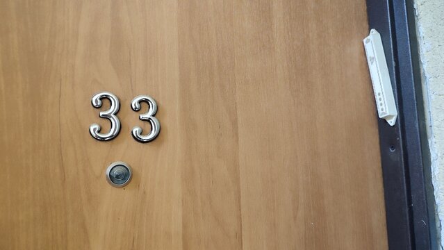 numbers 33 address on a white exterior apartment door, symbol objects, sky