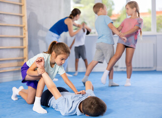 Children boy and girl partner in sparring practice technique practicing basic attacking movements and maneuvers. Class self-defense training in presence of experienced instructor