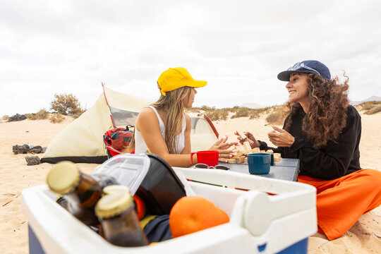 A happy couple engages in a playful game of Jenga at their beachside camp, sharing smiles and memories