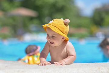 A small child next to the pool in a cap