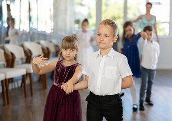 Active preteen children practicing ballroom dances in pairs during dancing classes