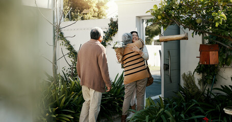 Happy family, open door and hug with flowers outdoor of home in backyard with daughter and parents with love. Reunion, welcome and woman with mom and dad, travel and surprise for holiday with embrace