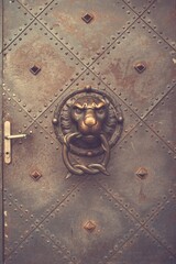 Vintage door with lion head knocker and decorative studs.