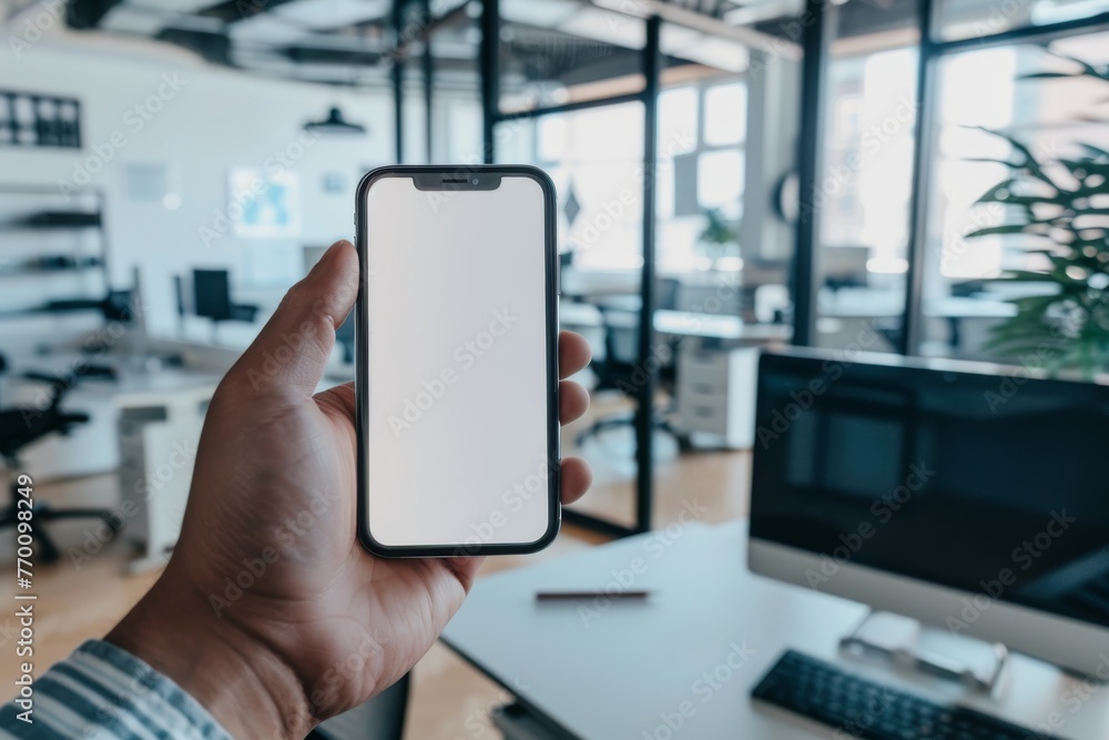 Poster A person showing a smartphone with an empty screen ready for your mock-up in a casual office setting