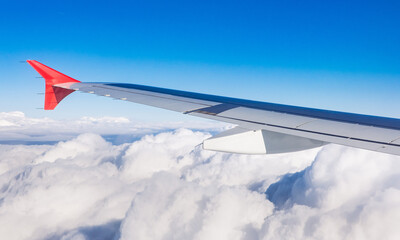 wing of airplane above fluffly clouds  - 770100635