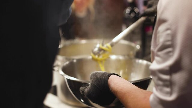 Group of people in a cooking class studio, adults preparing different dishes in the kitchen together, people in aprons learn on culinary master class, chef uniform, hands in gloves, italian cuisine