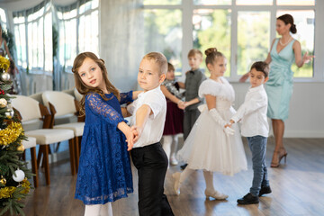Christmas ball - group of preteen children in festive clothes dances a foxtrot near the New Year...
