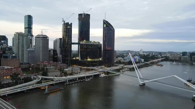 Aerial drone view rotating and rising up above Brisbane central business district, QLD, Australia along Brisbane River during the late afternoon in March 2024 