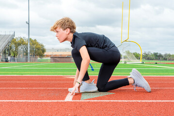 Young male track runner in the starting position, head up about to race