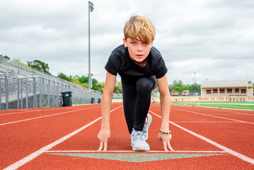 Young male track runner in the starting position, head up about to race