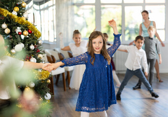 Happy preteen girl in blue lace dress dancing energetic rock n roll with boy during cheerful...