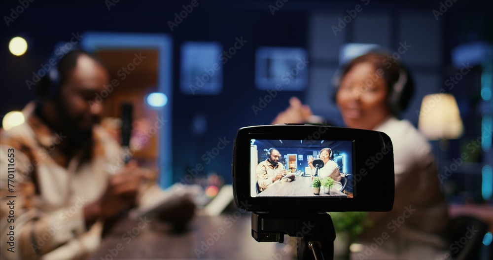 Poster focus on professional camera recording vlogger show host in blurry background interviewing guest in 