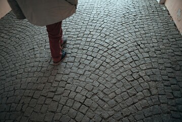 person wearing black shoes walking on a cobblestone walkway