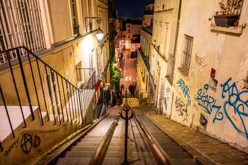 A tranquil evening view down the famous stairway of Montmartre, Paris, with warm streetlights and graffiti art. France