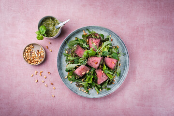 Traditional mixed salad with spinach filled roast beef rolls and pine nuts served as top view on a...