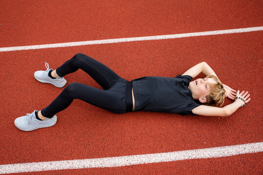 Youth male track runner collapsed on the track exhausted after a race
