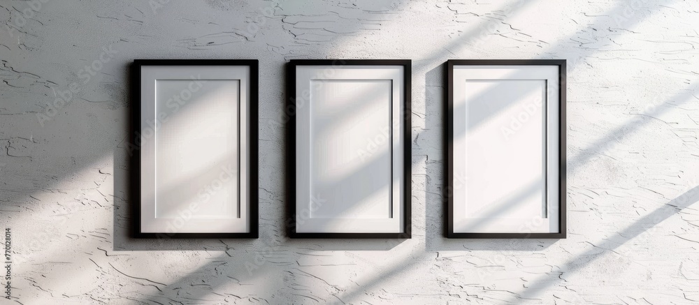 Wall mural Mockup of three empty photo frames on a white textured wall