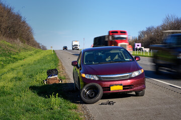 My wife stands well off to the side of the road after getting a flat tire on a very busy highway...