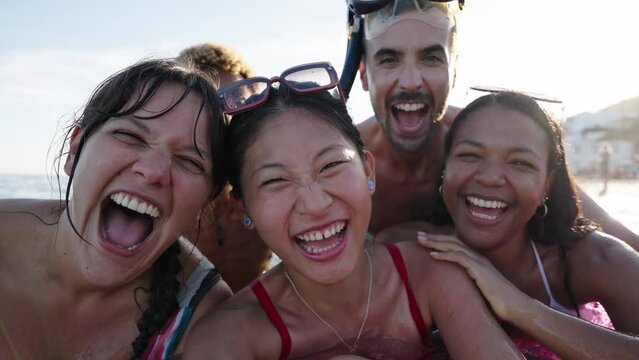 Selfie time. Group of cheerful multiracial friends in swim wear and diving goggles, caps, inflatable mats, are posing for a photo, that Asian lady is taking, beaming smiles, sunshine