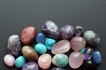 Multi-colored semi-precious stones on a gray background. Healing crystals.