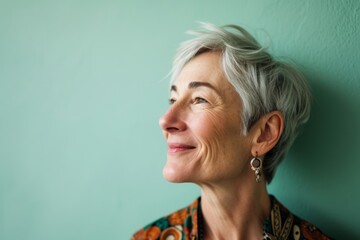 Portrait of a happy senior woman with short gray hair against green wall