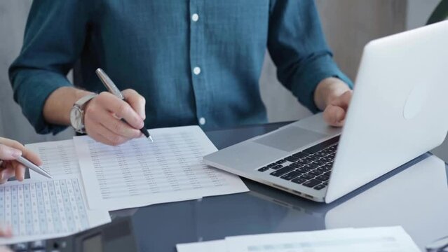 Business people professionals analyzing data on laptop. Close-up of auditor's hands reviewing financial spreadsheets in a modern office setting. Finance teamwork