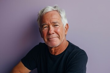 Portrait of a senior man with grey hair against purple background.