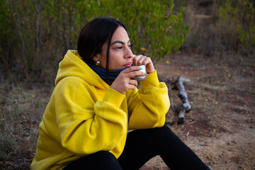 Mexican girl seated in the countryside with a cup of coffe