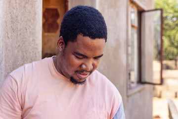 young african man with a goatee standing in front of the house, african village life