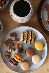 Cup of tea or coffee, cookies, macaroons, chocolate, various nuts and cocoa powder on wooden table. Top view.
