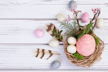 Easter decoration nest with eggs, flowers, branches and feathers.