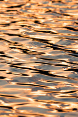 Water ripples reflecting off the sun at sunset in a vibrant collection of colors