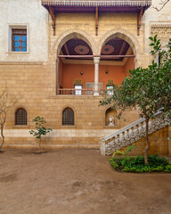 Fototapeta na wymiar Serene courtyard showcases the timeless beauty of Mamluk architecture with high big arches and stonework with welcoming staircase leading to ornate balcony