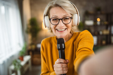 One woman mature blonde hold microphone at home happy smile sing dance